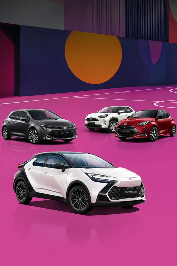 Ein weißer Toyota C-HR, ein silberner Corolla, ein weißer Yaris Cross und ein roter Yaris stehen auf einem bunten, mit lilanen, roten und blauen Mustern versehenen Basketballplatzes