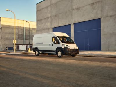 Drei Toyota Transporter (Proace Max, Proace, Proace City) schräg von vorne auf einem Parkplatz, dahinter große Stapel mit Europaletten