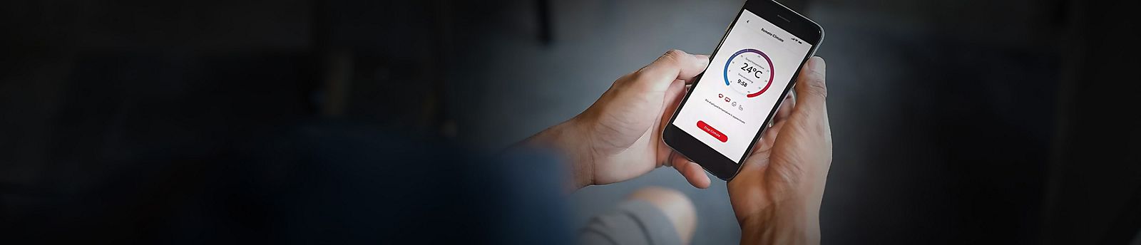 Smartphone in der Hand einer Person, darauf eine App zum Bedienen der Klimatisierung zu sehen.