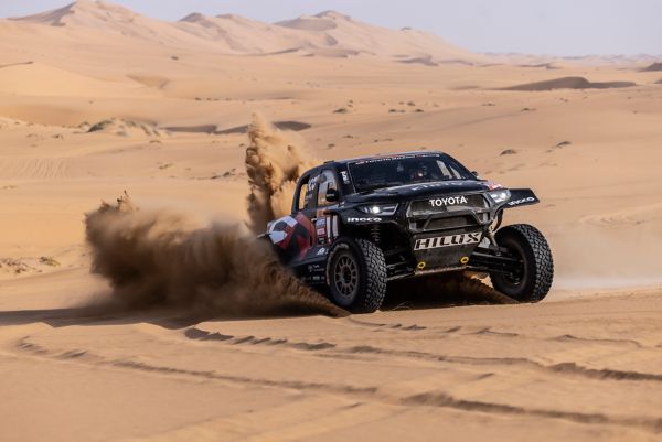 Low angle front on Hilux driving up desert dune