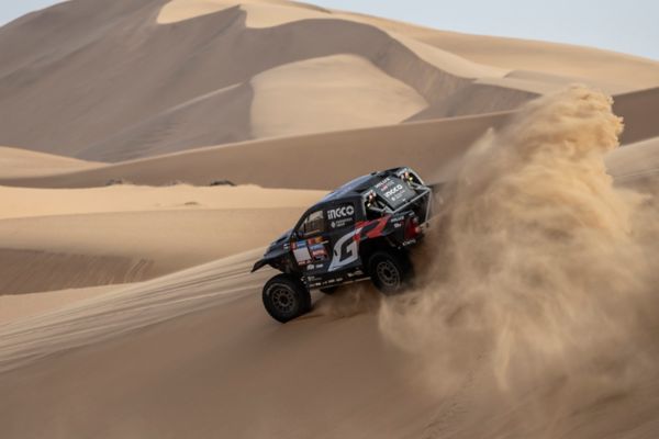 Hilux ripping through desert kicking up sand