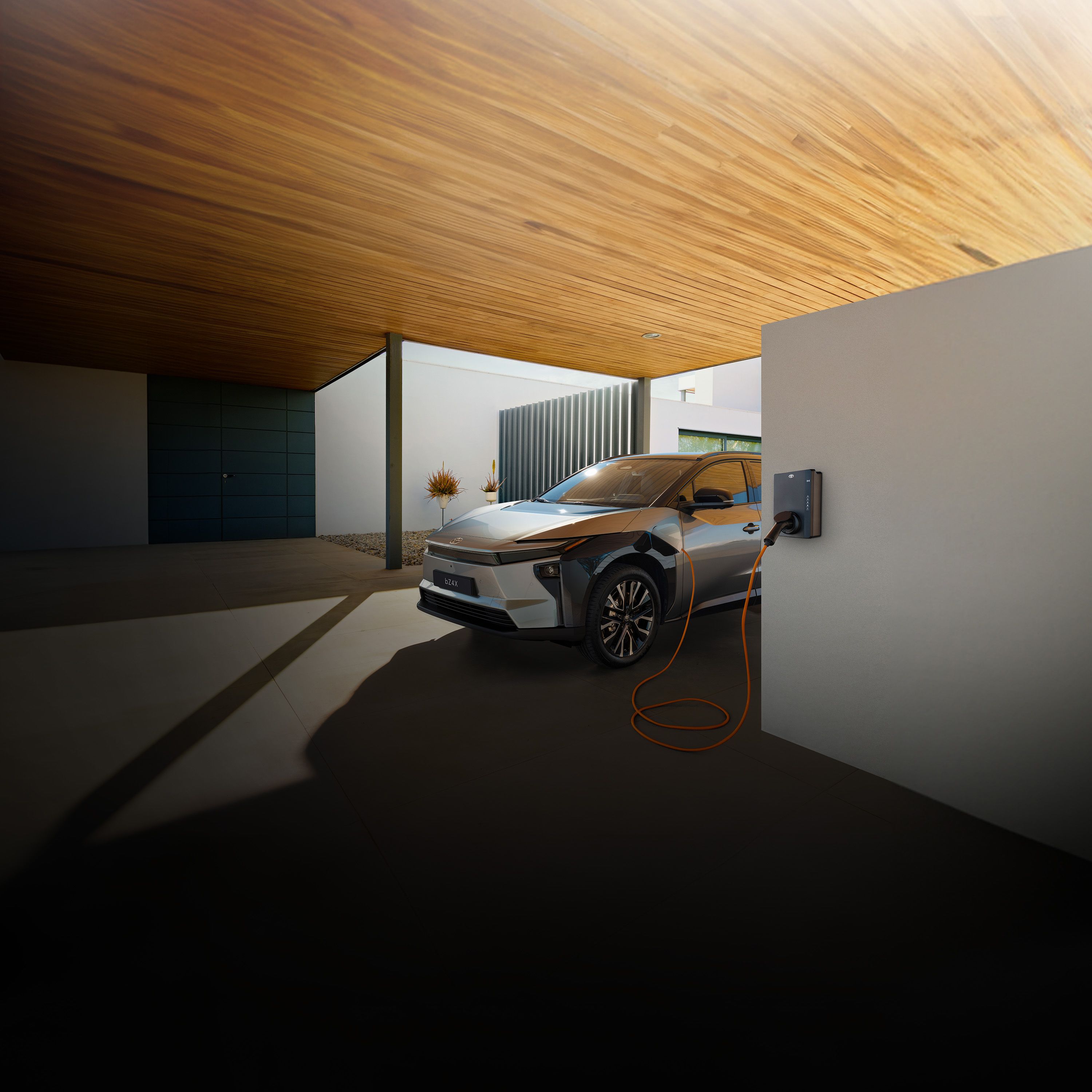 Silberner Toyota Elektro-SUV steht unter einem Carport an einer Wallbox und lädt.