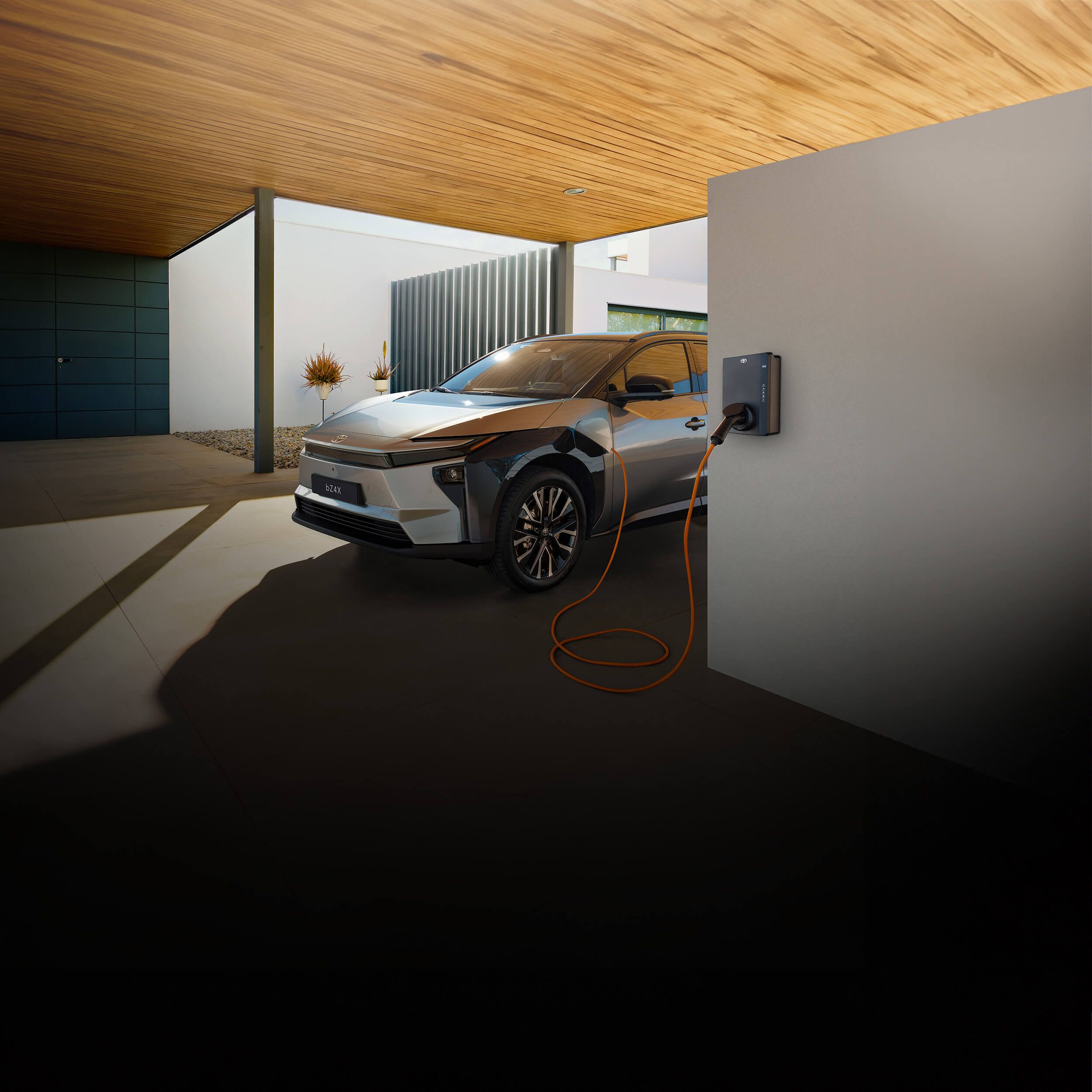 Silberner Toyota Elektro-SUV steht unter einem Carport an einer Wallbox und lädt.