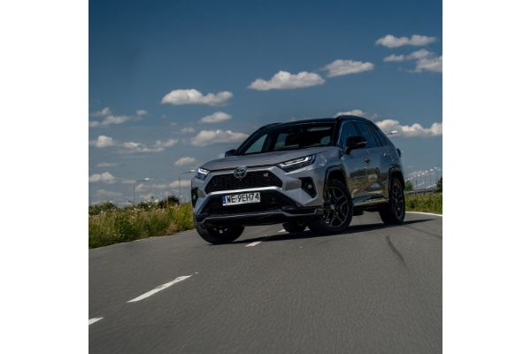 Toyota RAV4 z czarnymi felgami i sportowymi detalami, jadąca po drodze w słoneczny dzień