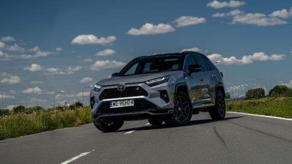 Toyota RAV4 z czarnymi felgami i sportowymi detalami, jadąca po drodze w słoneczny dzień