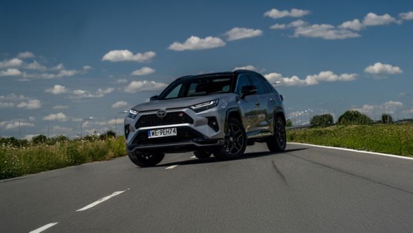Toyota RAV4 z czarnymi felgami i sportowymi detalami, jadąca po drodze w słoneczny dzień
