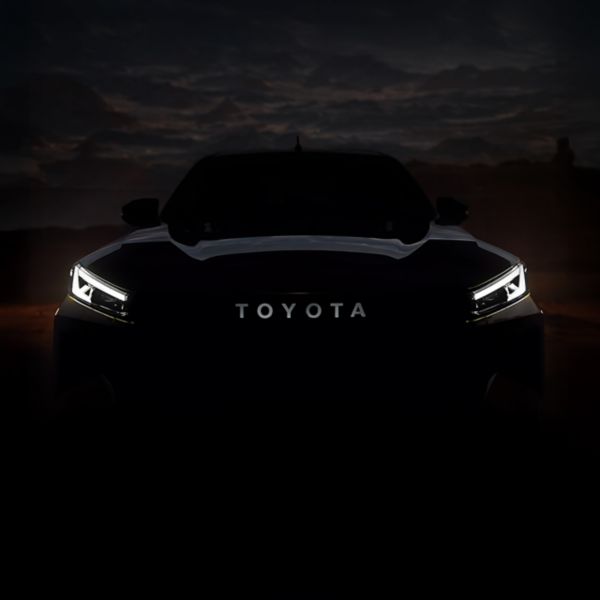 Frontansicht eines Toyota mit leuchtenden LED-Scheinwerfern bei Dämmerung.