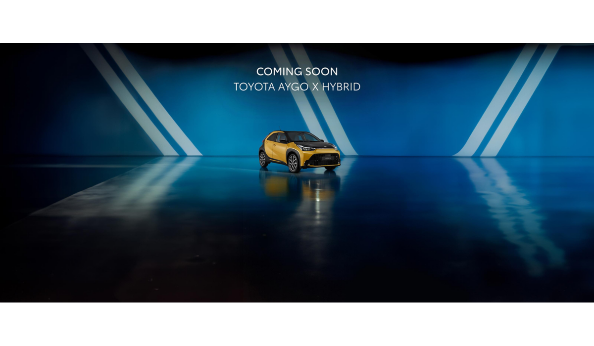 Ein Aygo X mit schwarz-gelber Lackierung steht diagonal zur Kamera vor einem blauen Hintergrund. Über dem Auto steht ein Text: Coming Soon: Toyota Aygo X Hybrid