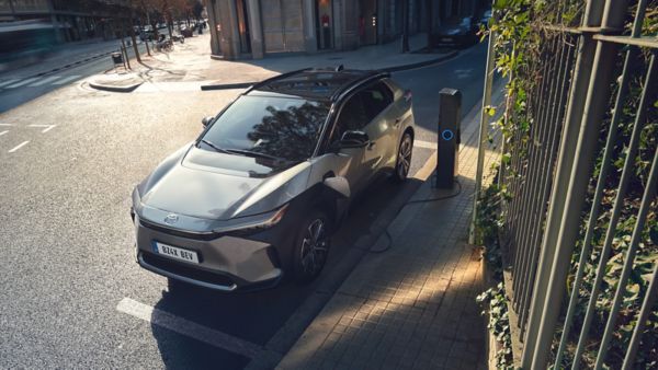 Ein silberner Toyota SUV steht am Straßenrand und lädt an einer Ladesäule.