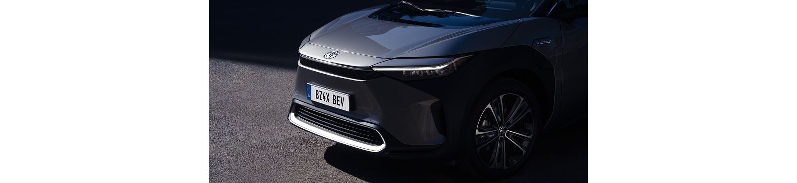 Nahaufnahme der Front des Toyota bZ4X, der geparkt steht und von der Sonne angestrahlt wird.