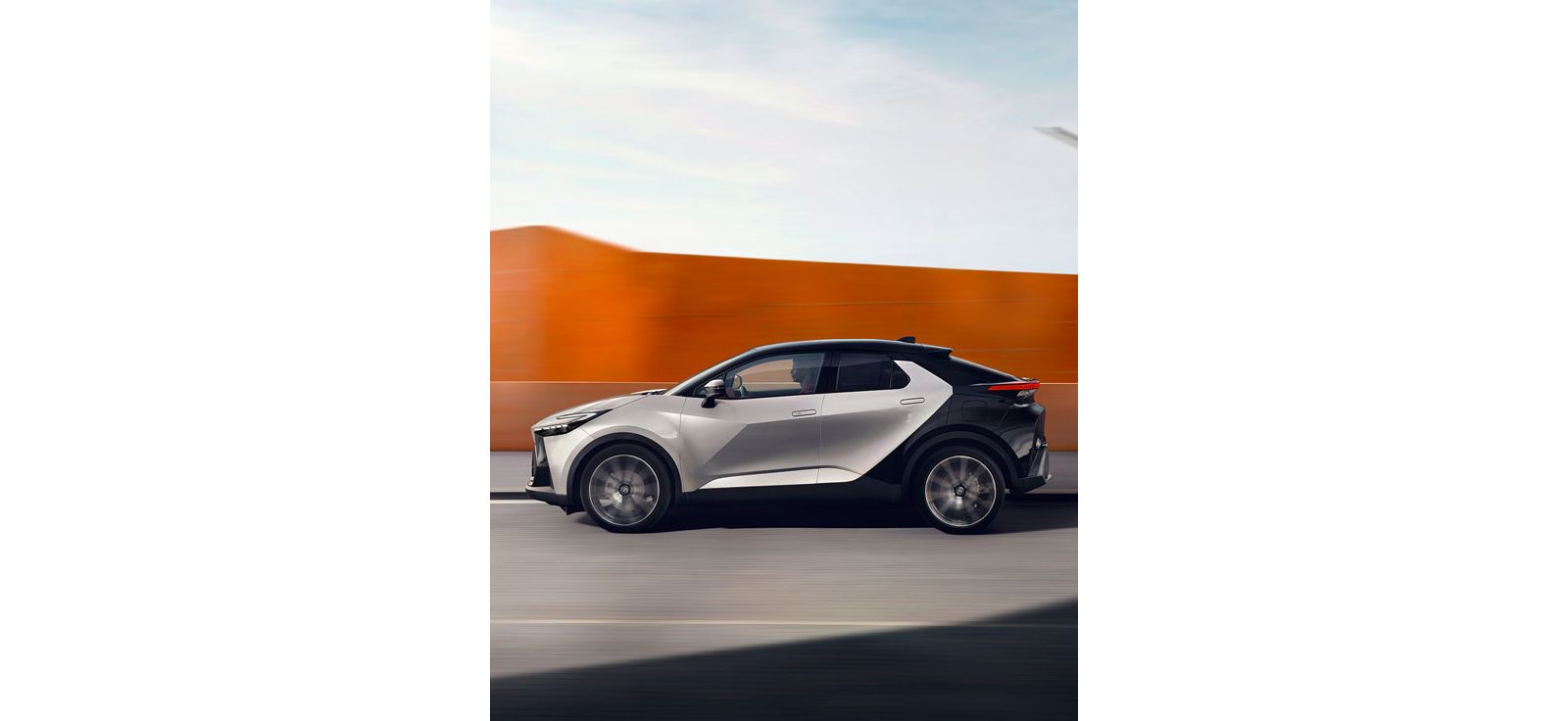 Seitenansicht auf einen silber-schwarzen Toyota C-HR bei der Fahrt. 