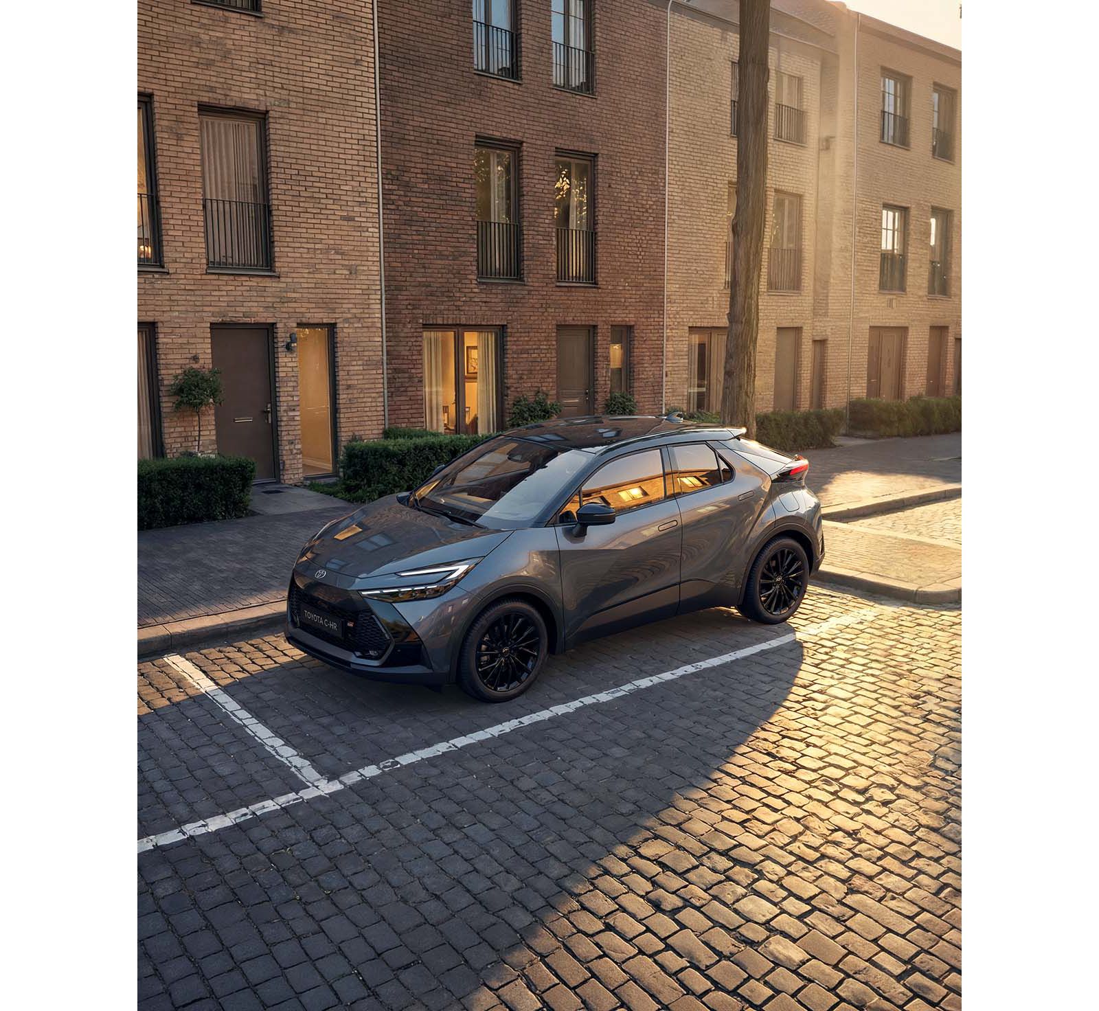 Toyota C-HR auf einem Parkplatz vor modernen Wohnhäusern.