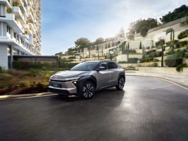 Silberner Toyota Elektro-SUV fährt um eine Kurve in einem Wohngebiet.