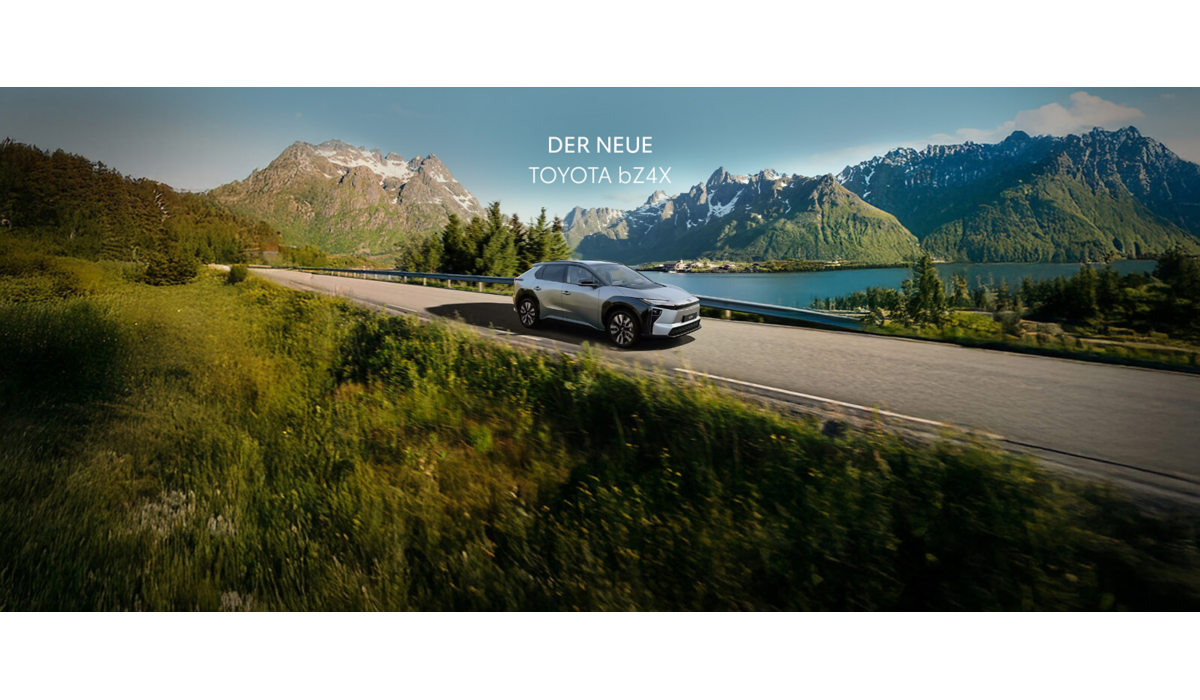 Silberner Toyota bZ4X fährt auf einer von Bäumen und grünen Sträuchern eingerahmten Straße. Im Hintergrund geht die Sonne hinter Bergen unter. Text darüber: Der neue Toyota bZ4X.
