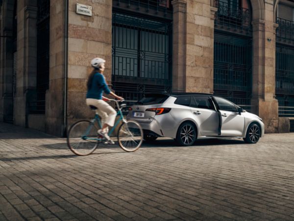 toyota-corolla-touring-sports-exterieur-driekwart-rechtsachter-met-fietser-zilvergrijs