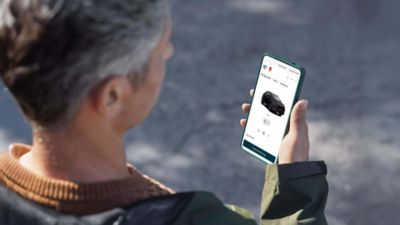 Blick von hinten auf eine Person, die auf ein Smartphone schaut.