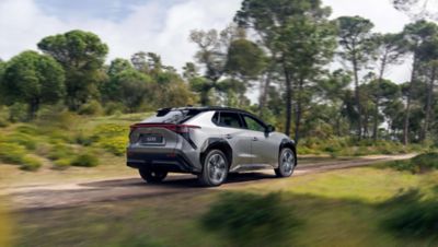 Ein elektrischer SUV fährt auf einer unbefestigten Landstraße.