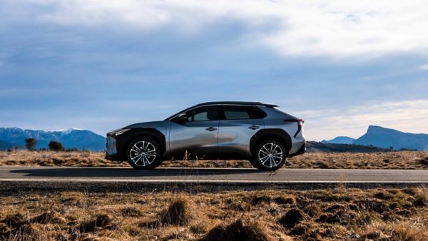 Ein silber-schwarzer Toyota bZ4X fährt auf einer Straße durch eine karge Steppenlandschaft, im Hintergrund sind Bergzüge zu sehen.