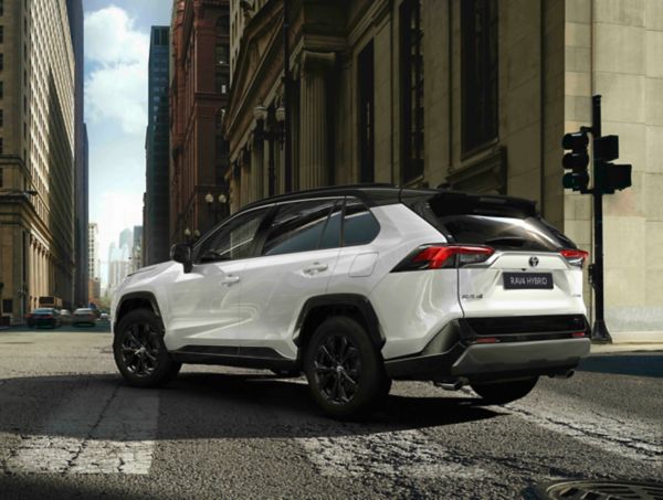 Ein weißer Toyota RAV4 fährt über einen Zebrastreifen durch die tiefen Straßenschluchten einer Innenstadt.