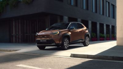 Person lädt Gepäck in einen geparkten Toyota Yaris Cross.
