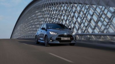 Grauer Toyota Kleinwagen fährt über eine Autobahnbrücke.