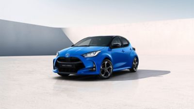 Blauer Toyota Yaris steht diagonal zur Kamera vor einem neutralem Hintergrund.