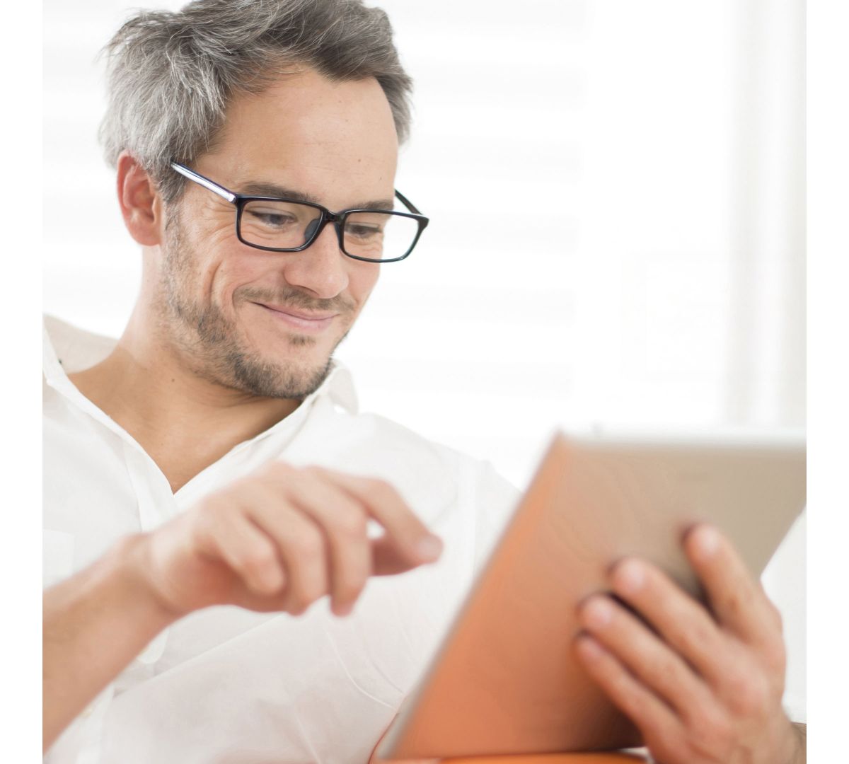 Ein Mann in weißem Hemd tippt auf einem Tablet, das er in der Hand hält