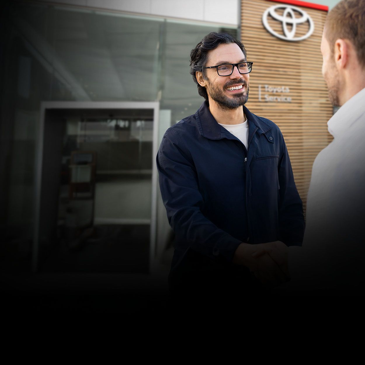 Zwei Männer stehen vor einem Toyota Autohaus und unterhalten sich