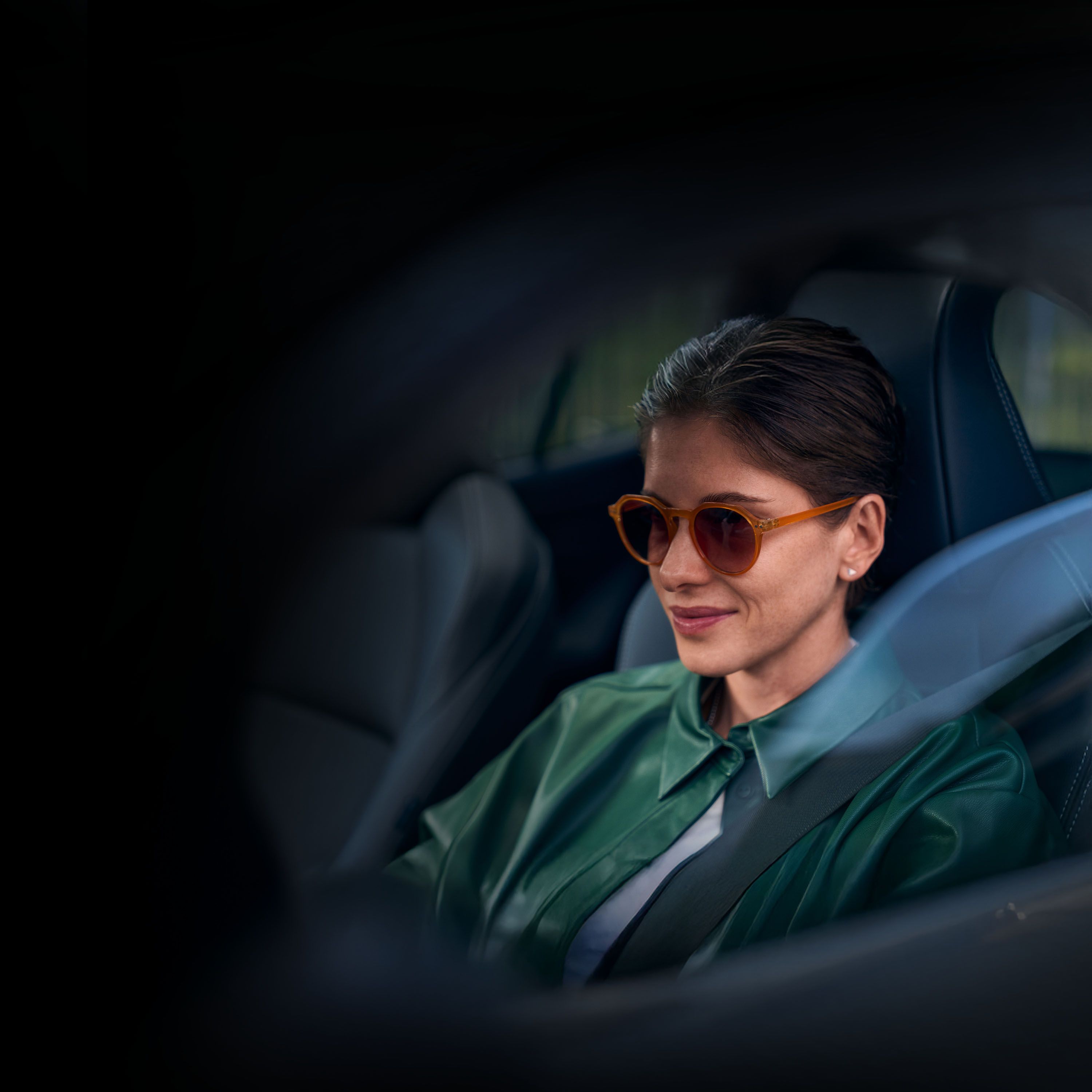 Eine Frau in grüner Jacke und mit dunkler Sonnenbrille sitzt am Steuer eines Toyota.