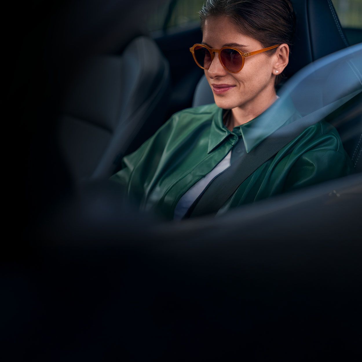 Eine Frau in grüner Jacke und mit dunkler Sonnenbrille sitzt am Steuer eines Toyota.