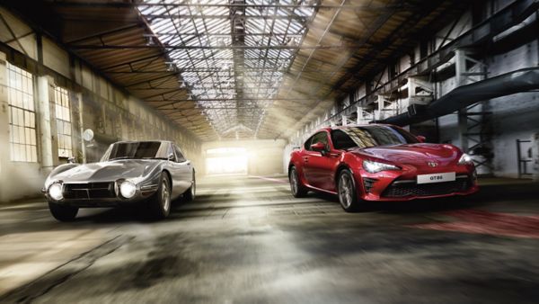 Toyota GT86 driving along a road next to an older version