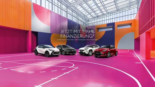 Vier Toyota Fahrzeuge auf dem Innenhof eines modernen Gebäudes mit Glasfront, Bildtext: „LAST MINUTE DEALS, 1,99% EASY FINANZIERUNG“