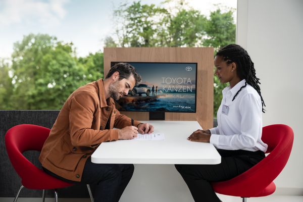 a customer signing a form in front of a Toyota employee