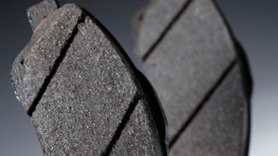 Detailaufnahme von zwei abgenutzten Bremsbelägen, die die Oberflächenstruktur und die Verschleißspuren deutlich zeigen.