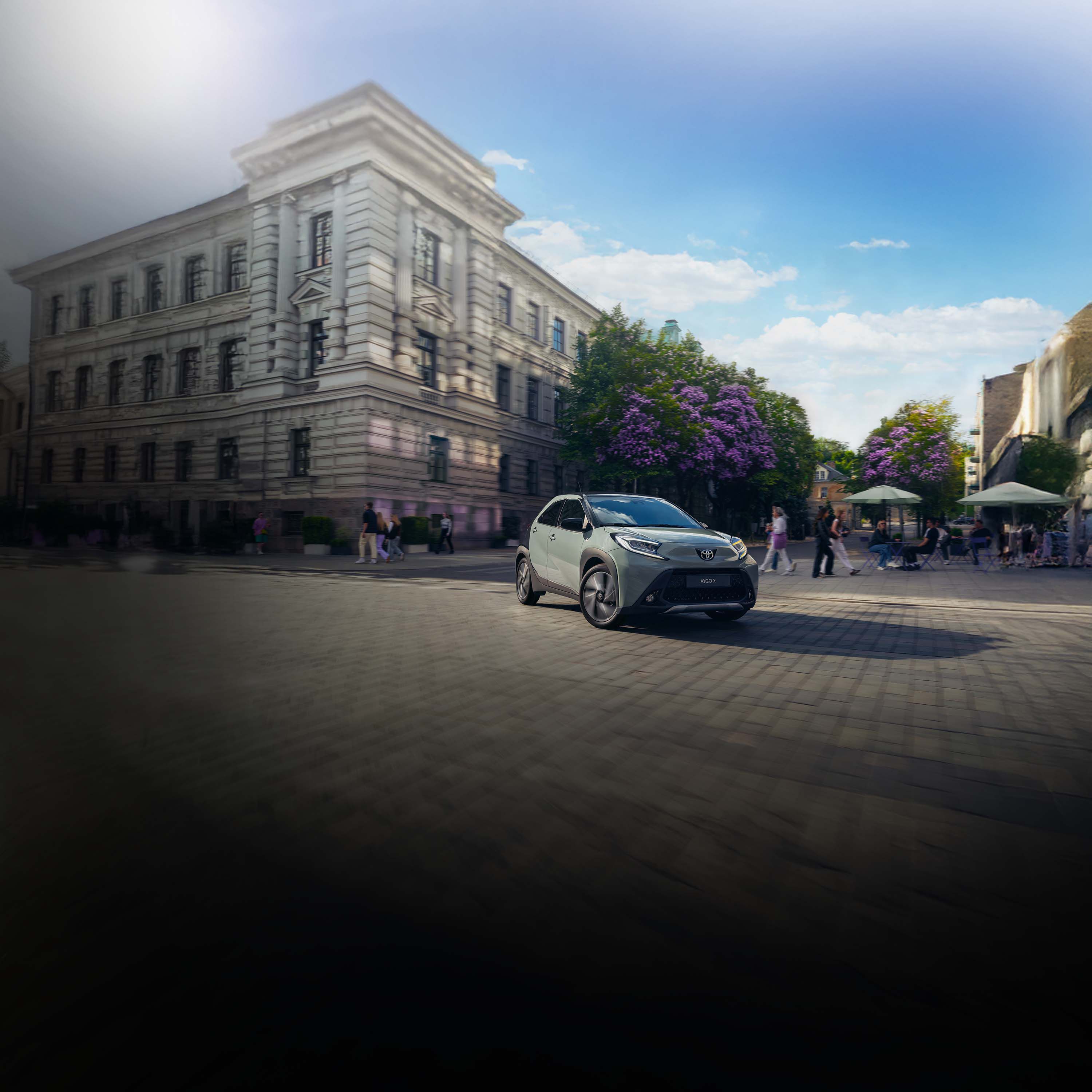 Kleinwagen fährt in einer Innenstadt aus einer schmalen Gasse heraus und biegt ab.