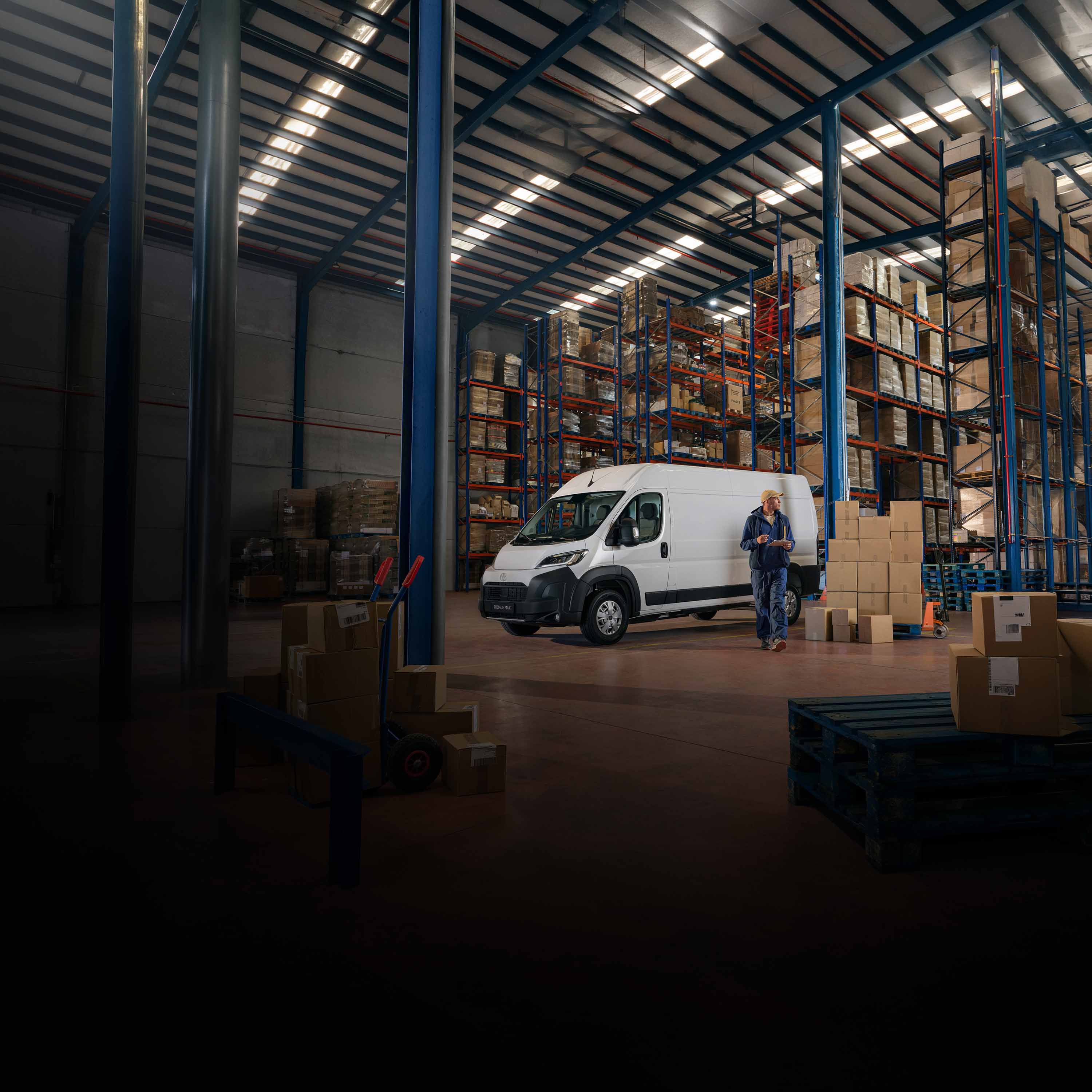 Toyota Proace Transporter steht in einer Lagerhalle zwischen Regalen und Versandkartons.