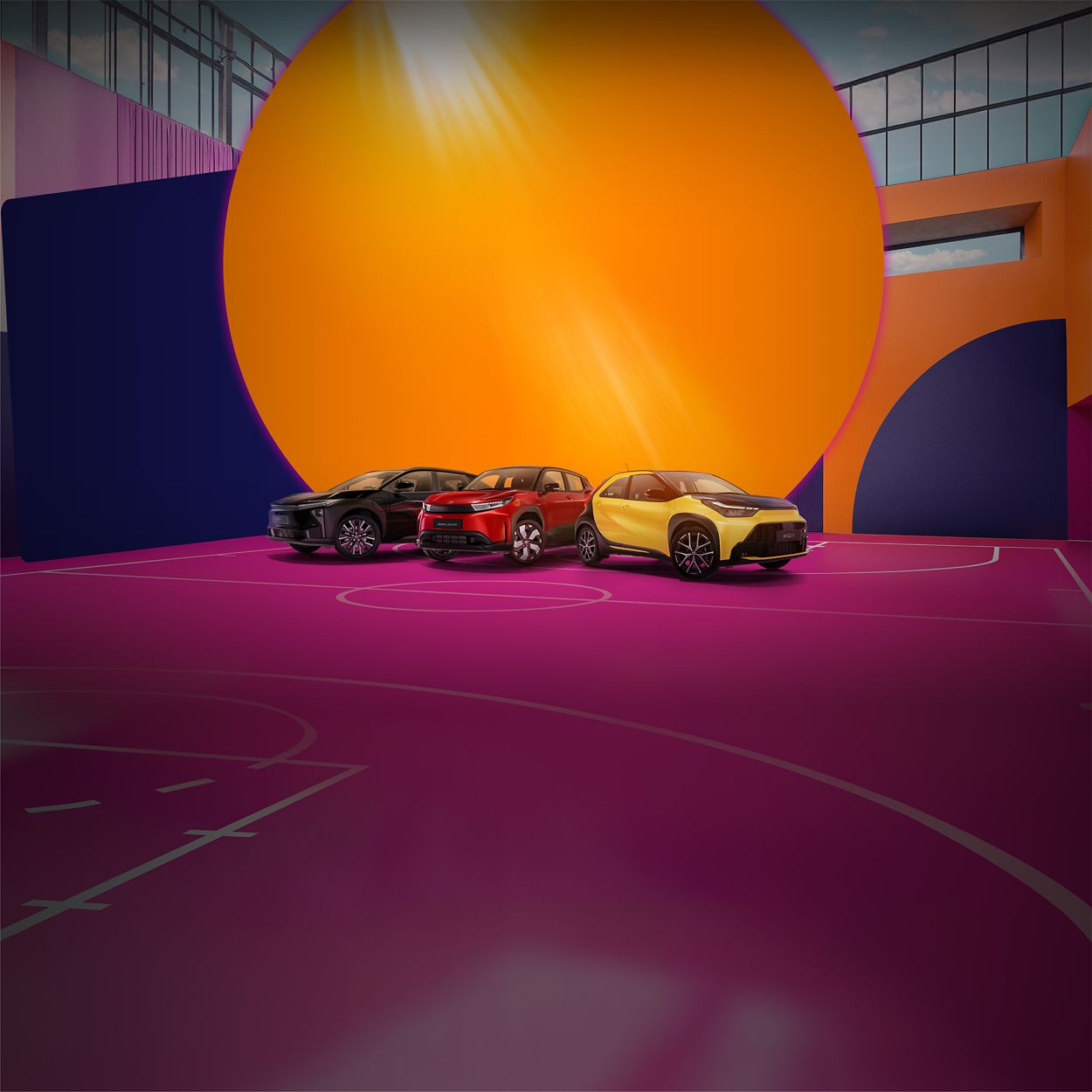 Vier Toyotas stehen auf einem pinken Basketballplatz, der von einer bunt bemalten Wand umgeben ist.