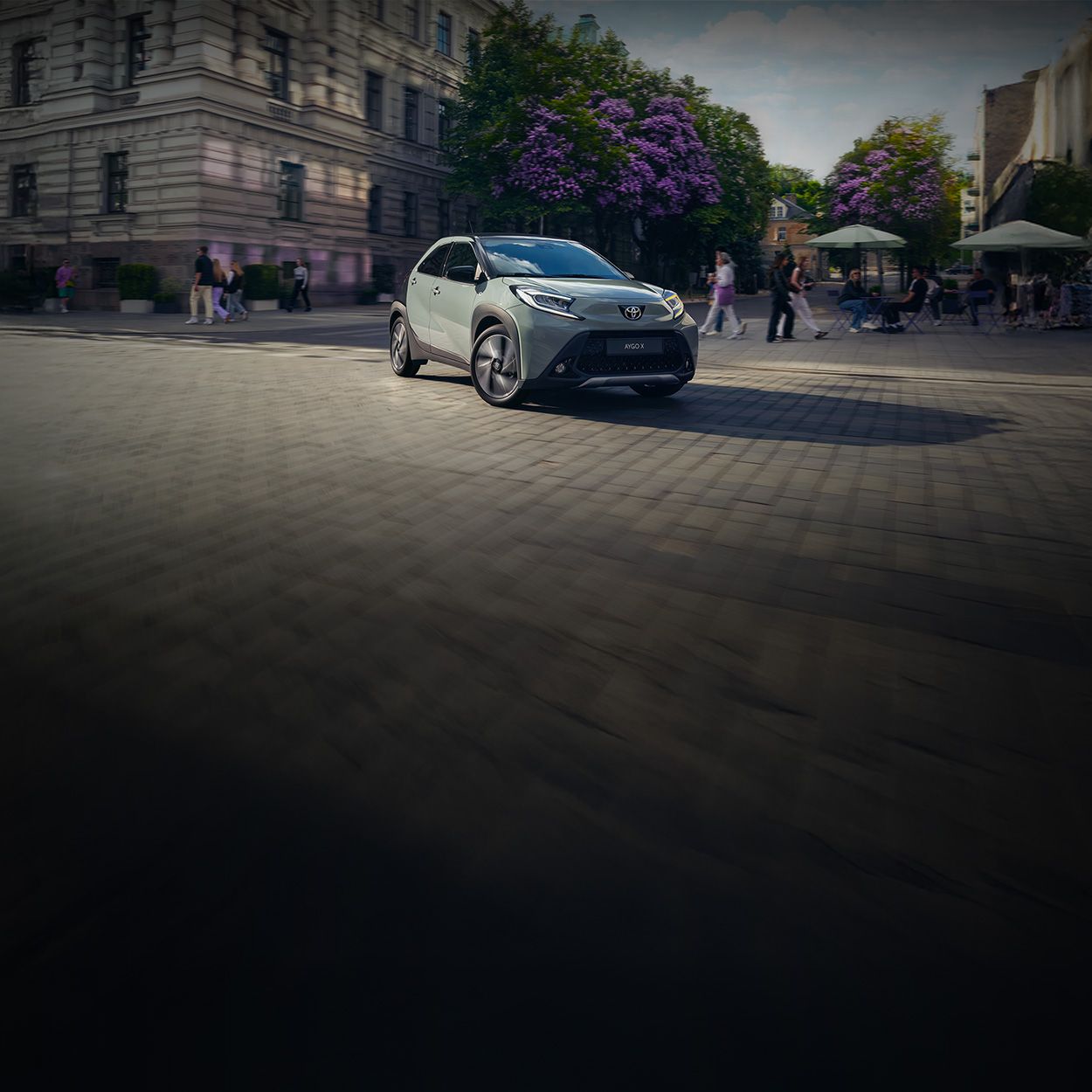 Kleinwagen fährt in einer Innenstadt aus einer schmalen Gasse heraus und biegt ab.