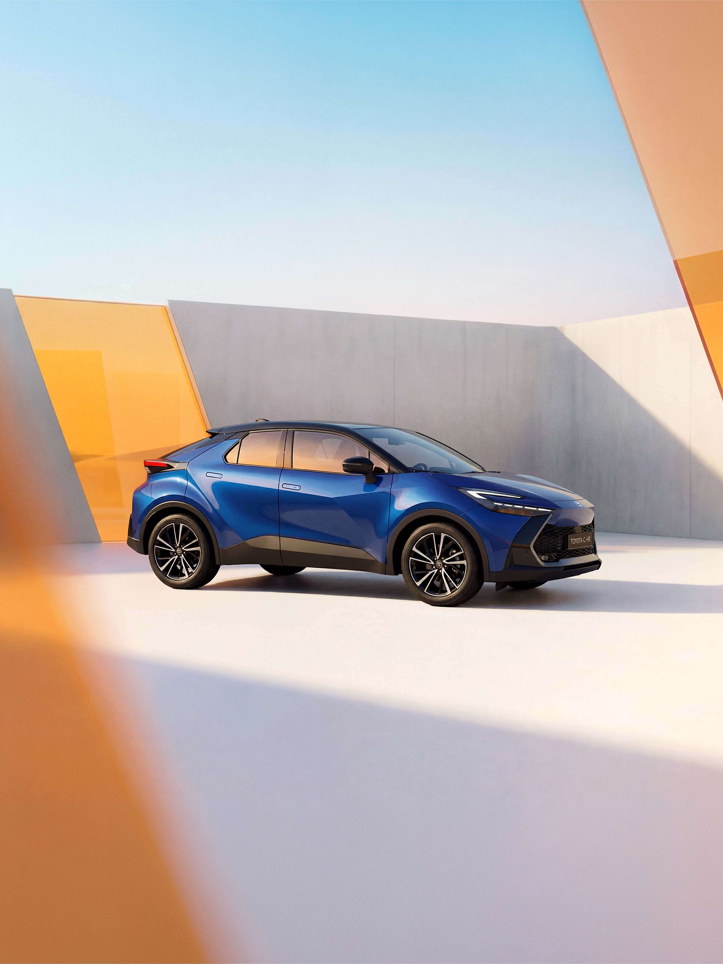 Blauer Toyota C-HR in moderner Architekturkulisse mit geometrischen Formen und warmem Licht.