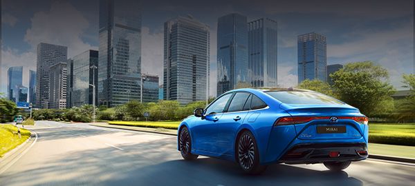 Toyota Mirai widziana od tyłu jedzie w kierunku miasta.