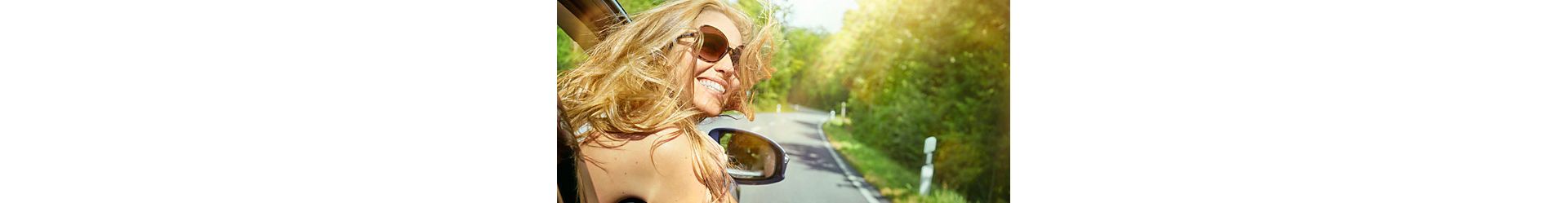 Happy woman leaning out car window 