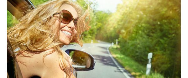 Happy woman leaning out car window 