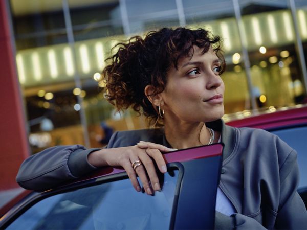 Eine Person steht vor einem Fahrzeug und schaut verträumt in die Ferne.