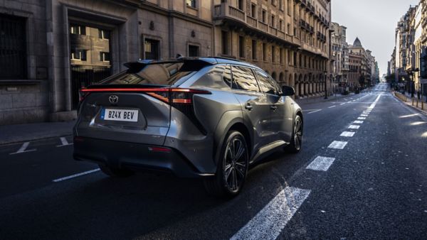 Rückansicht auf einen Toyota bZ4X der über eine Straße in einer Innenstadt fährt.
