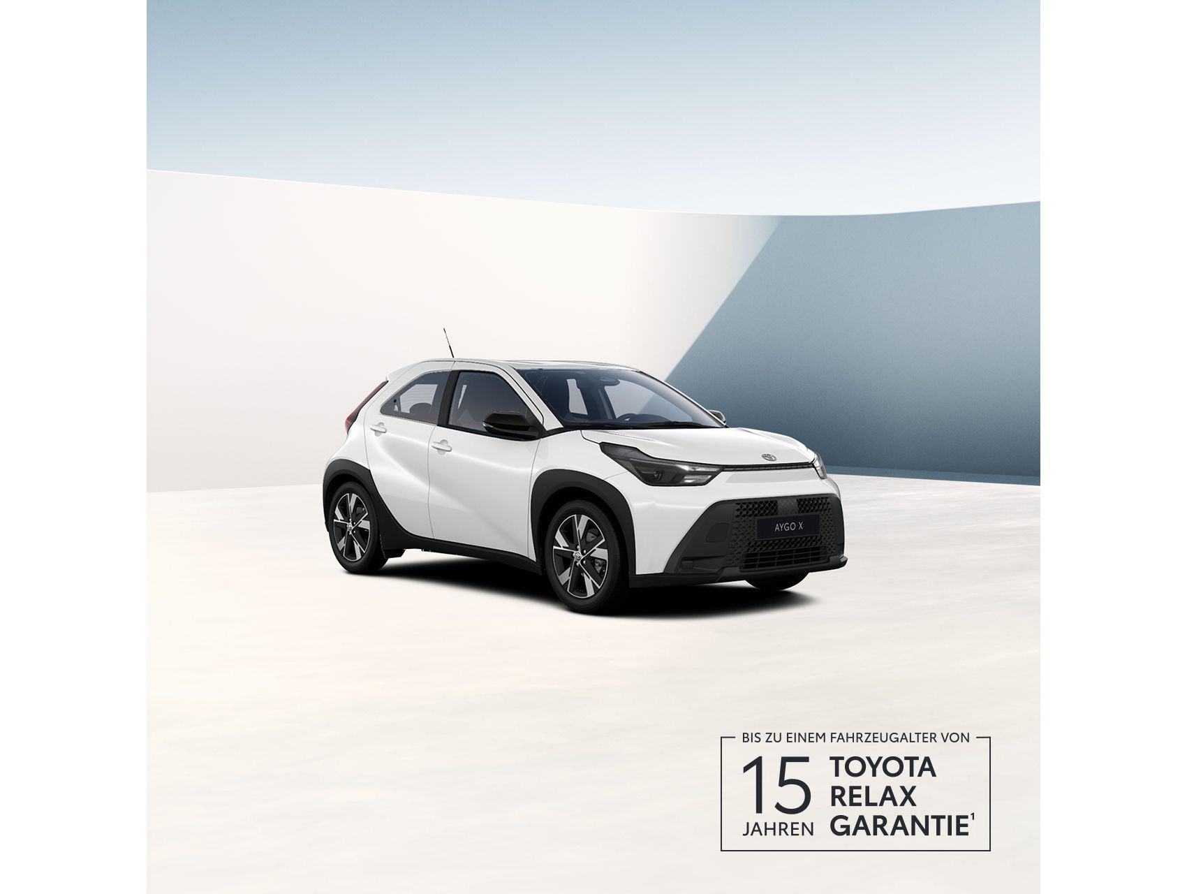 weißer Aygo X steht im 40 Grad nach rechts zur Kamera gedreht vor einem neutralen Hintergrund