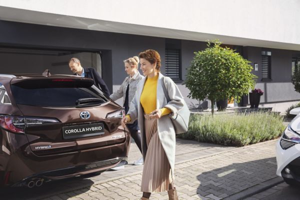 мъж и две жени слизат от Corolla Hybrid