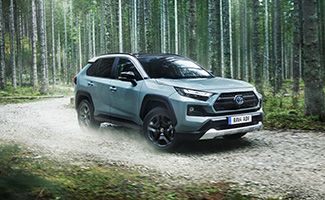 Toyota RAV4 jedzie po ulowej drodze przez brzozowy las