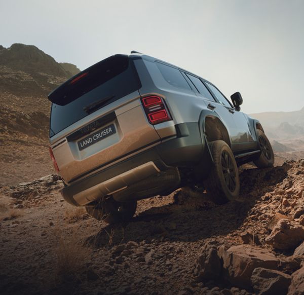 Silberner Land Cruiser fährt über ein schiefes Gelände.