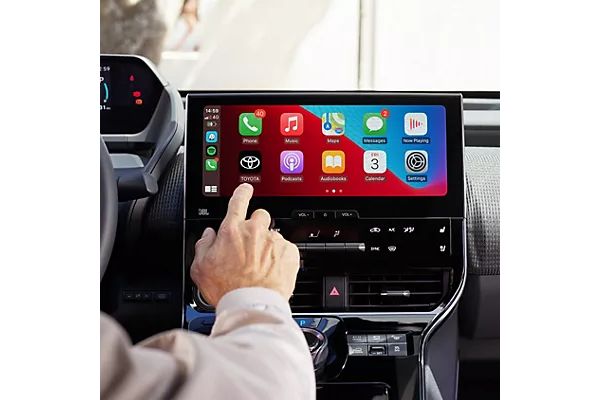 Perspektive von der Rückbank auf Mittelkonsole eines Autos, eine Person tippt auf eine App auf dem Touchscreen