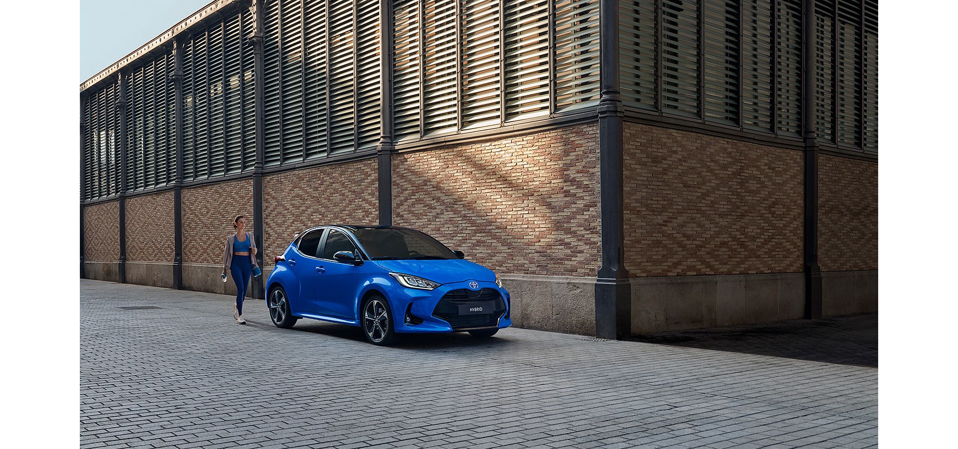 Woman in sportwear, walking towards a blue MC Yaris